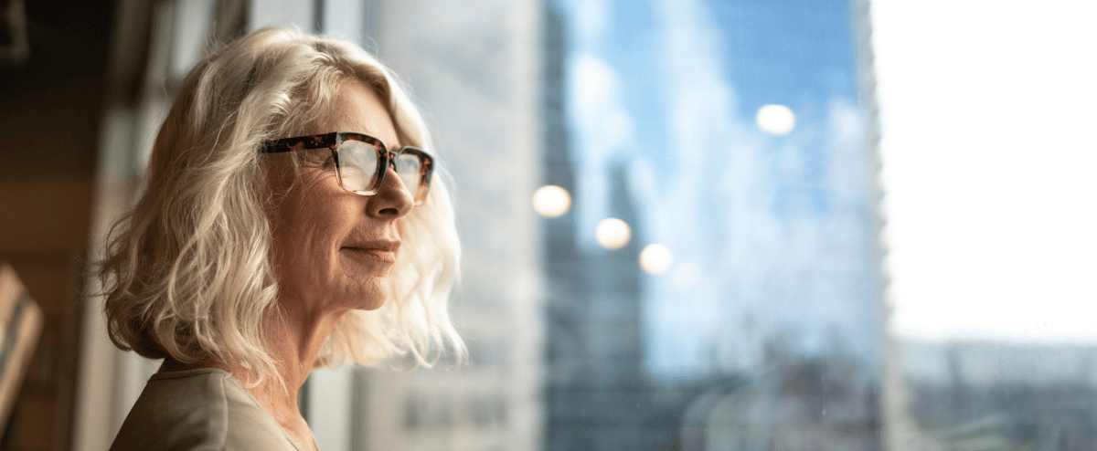 Person looking out window of office building, building self-awareness